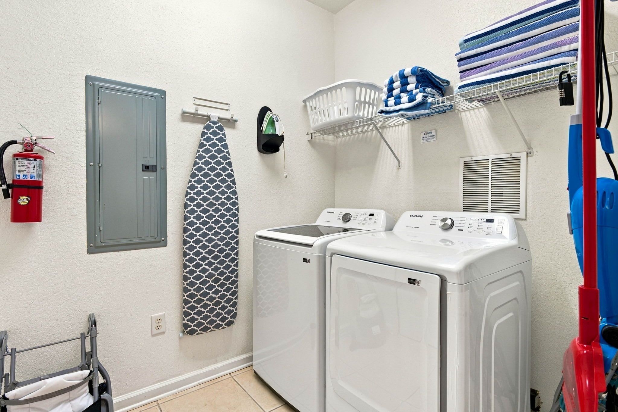 A laundry room with a washing machine, dryer, and a fire extinguisher.