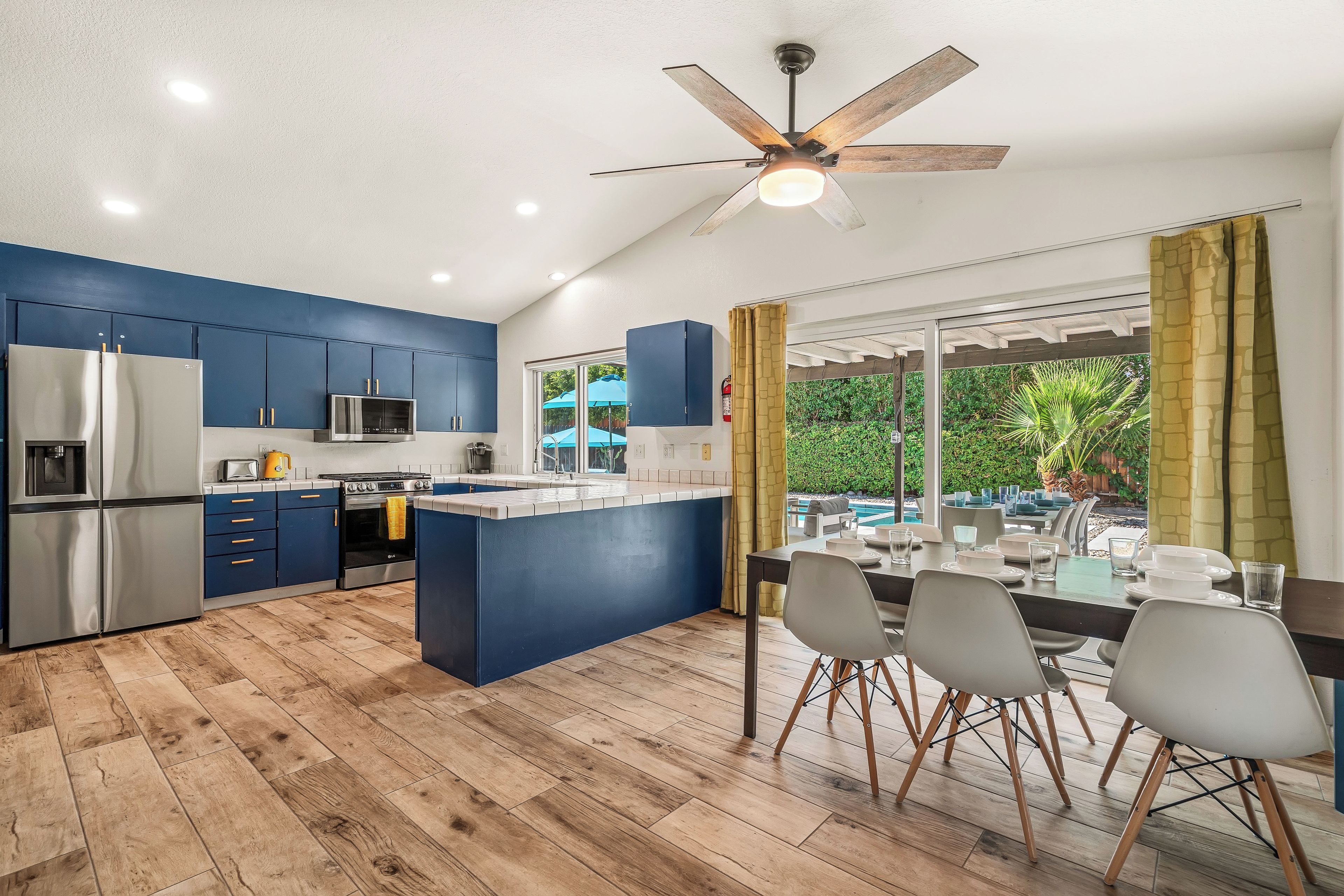 A modern kitchen with blue cabinets, a stainless steel refrigerator, and an island with a sink.