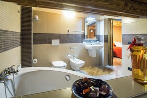 Een moderne badkamer met een bad, toilet, bidet en een wastafel.