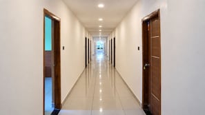 Un largo pasillo bien iluminado con puertas a ambos lados que dan acceso a habitaciones.
