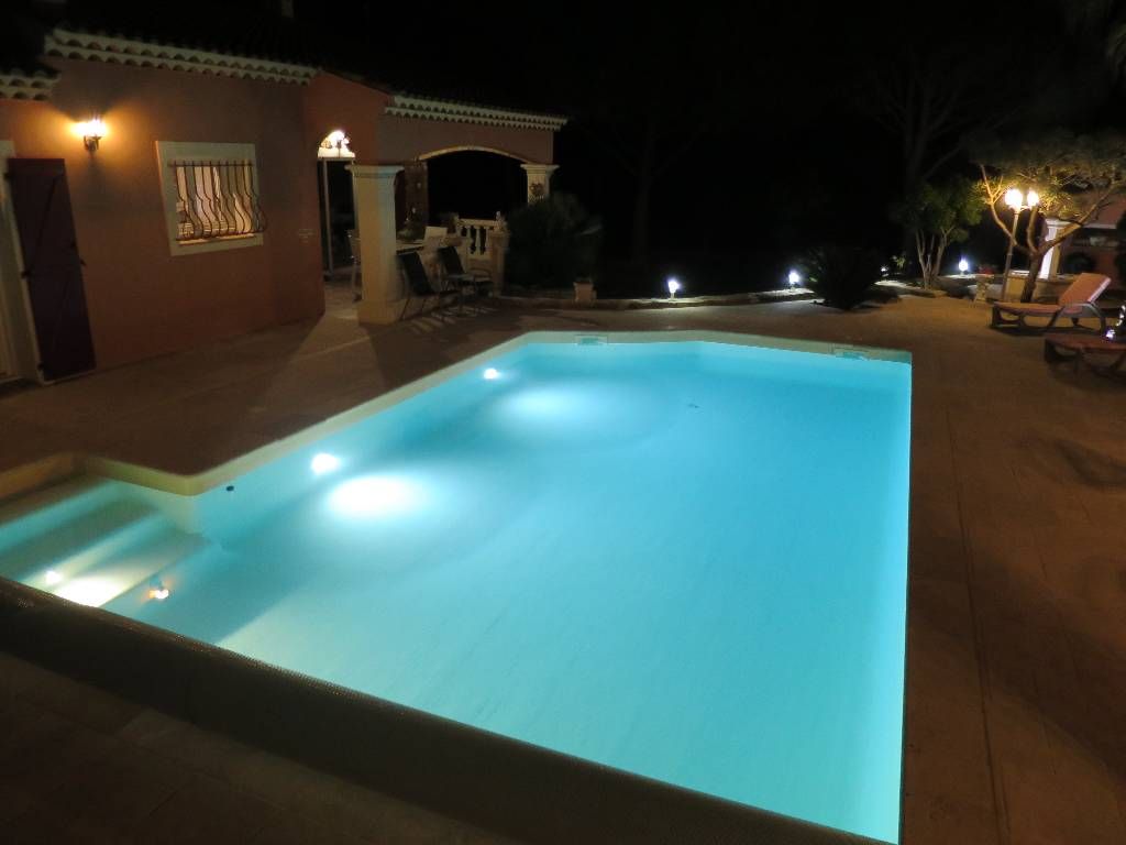 A swimming pool at night with lights around it.