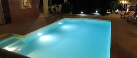 A swimming pool at night with lights around it.