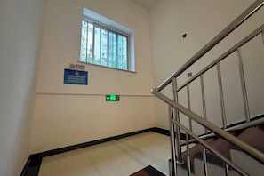 A stairwell with a metal railing, a window, and a sign indicating a smoking area. - Jiahe Liyuan Hotel (Beijing Tongren Hospital Beijing Railway Station) (Beijing)
