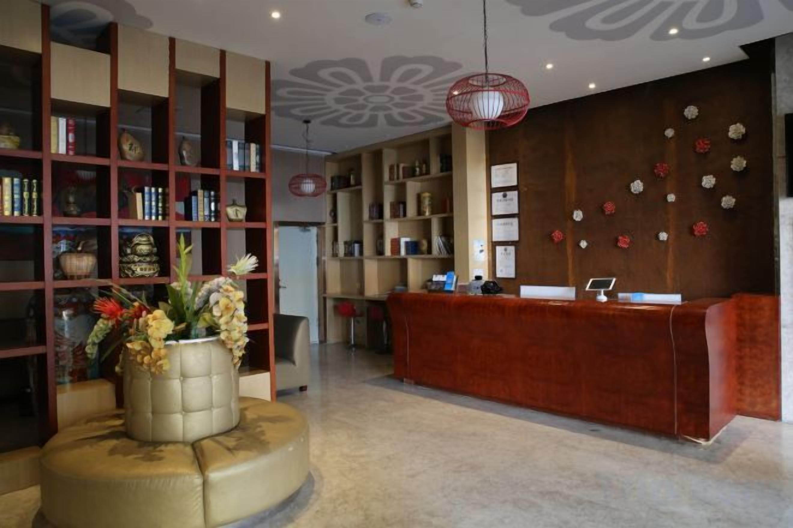 A reception area with a red desk, a bookshelf, and a decorative vase.