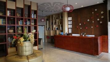 A reception area with a red desk, a bookshelf, and a decorative vase.