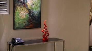 A room with a desk, a telephone, and a red abstract sculpture.