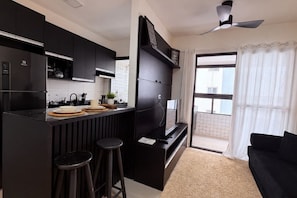 A modern kitchen with black cabinetry, a built-in stove, and a dining area with stools. - New Listing (Praia Grande)