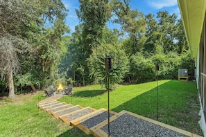Un jardin avec un foyer extérieur, un espace salon de jardin et un sentier.