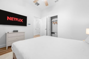 A bedroom with a bed, a dresser, a TV mounted on the wall, and a closet with clothes hanging. - Golf Views, Pool & Private Beach Access (Palm Coast)