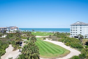 A golf course with a view of the ocean, surrounded by buildings and palm trees. - Golf Views, Pool & Private Beach Access (Palm Coast)