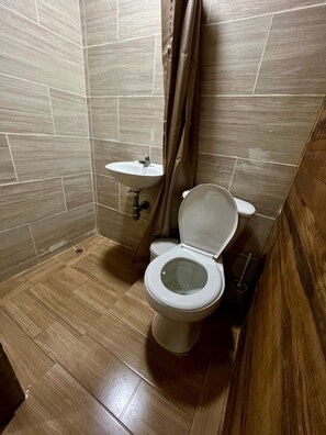 A small bathroom with a toilet, sink, and shower curtain.