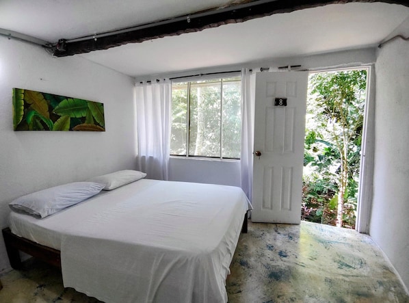 A room with a bed, a door, and a window.