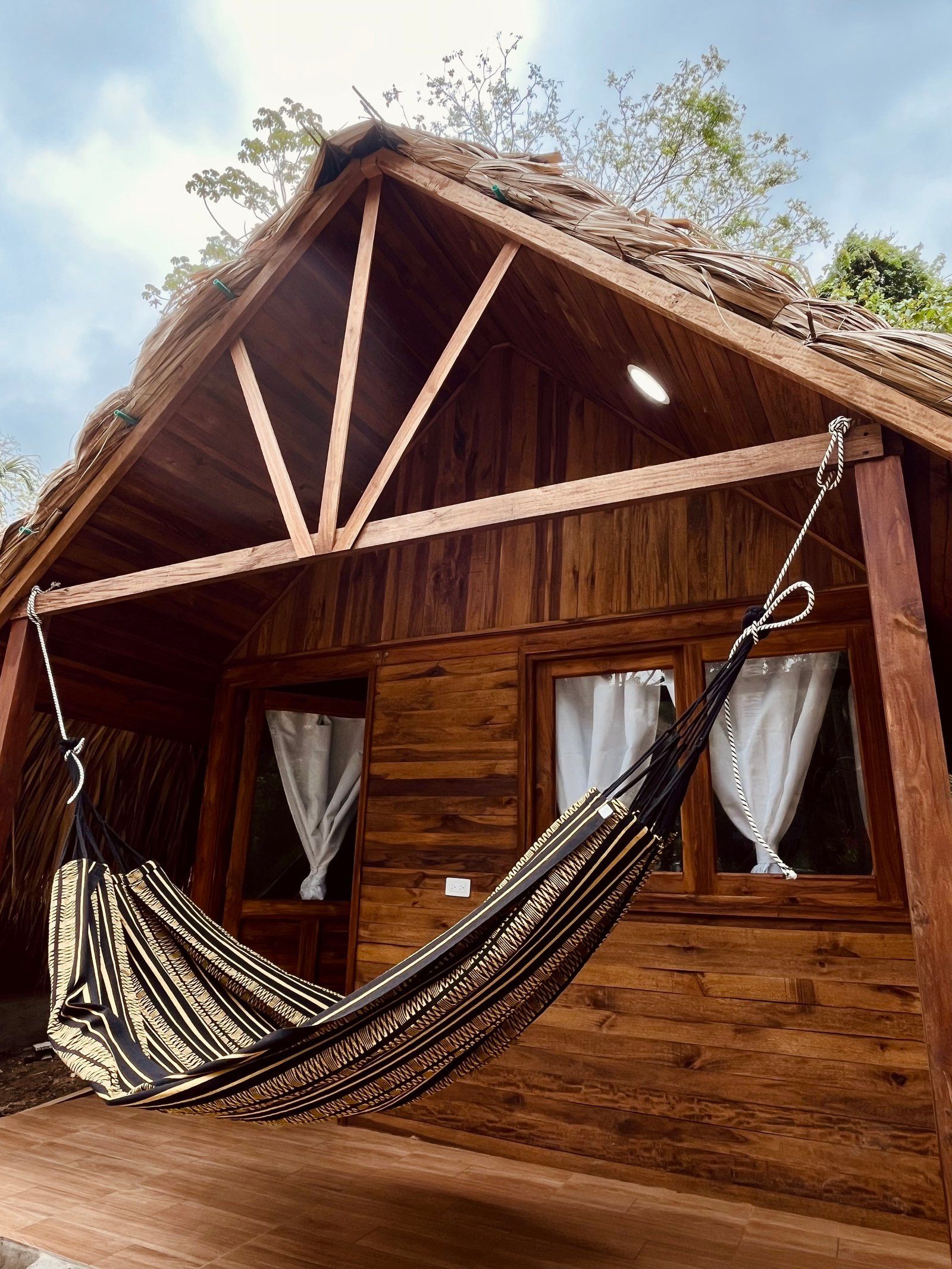 Een houten hutje met een hangmat aan de veranda.