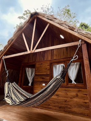 A wooden cabin with a hammock hanging from the porch.