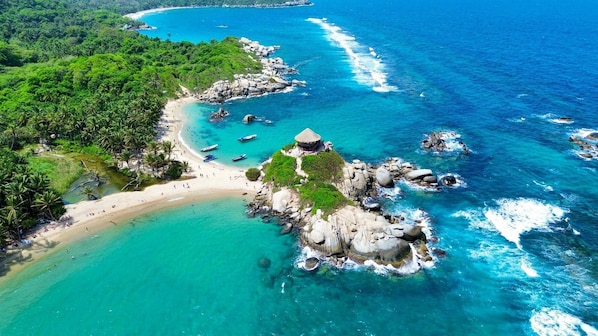 A coastal area with a beach, rocky outcrops, and clear turquoise waters.