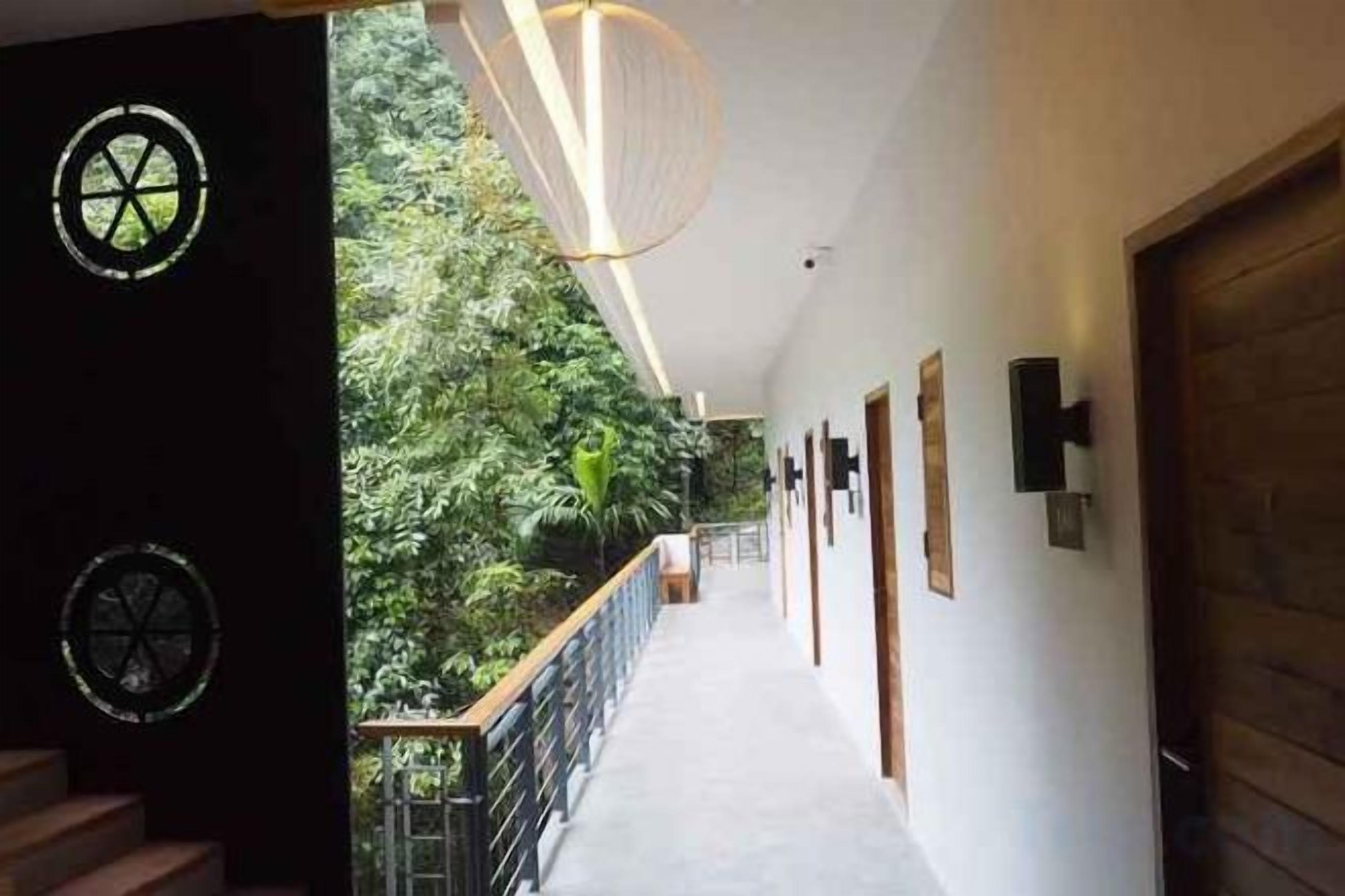 Un pasillo con una escalera de madera, barandilla y una puerta a la derecha.