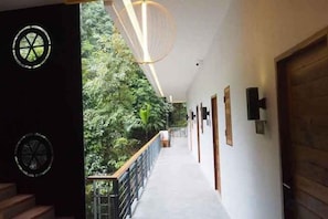 A corridor with a wooden staircase, a railing, and a door on the right. - Passion Resort Kiriwong (Lan Saka)