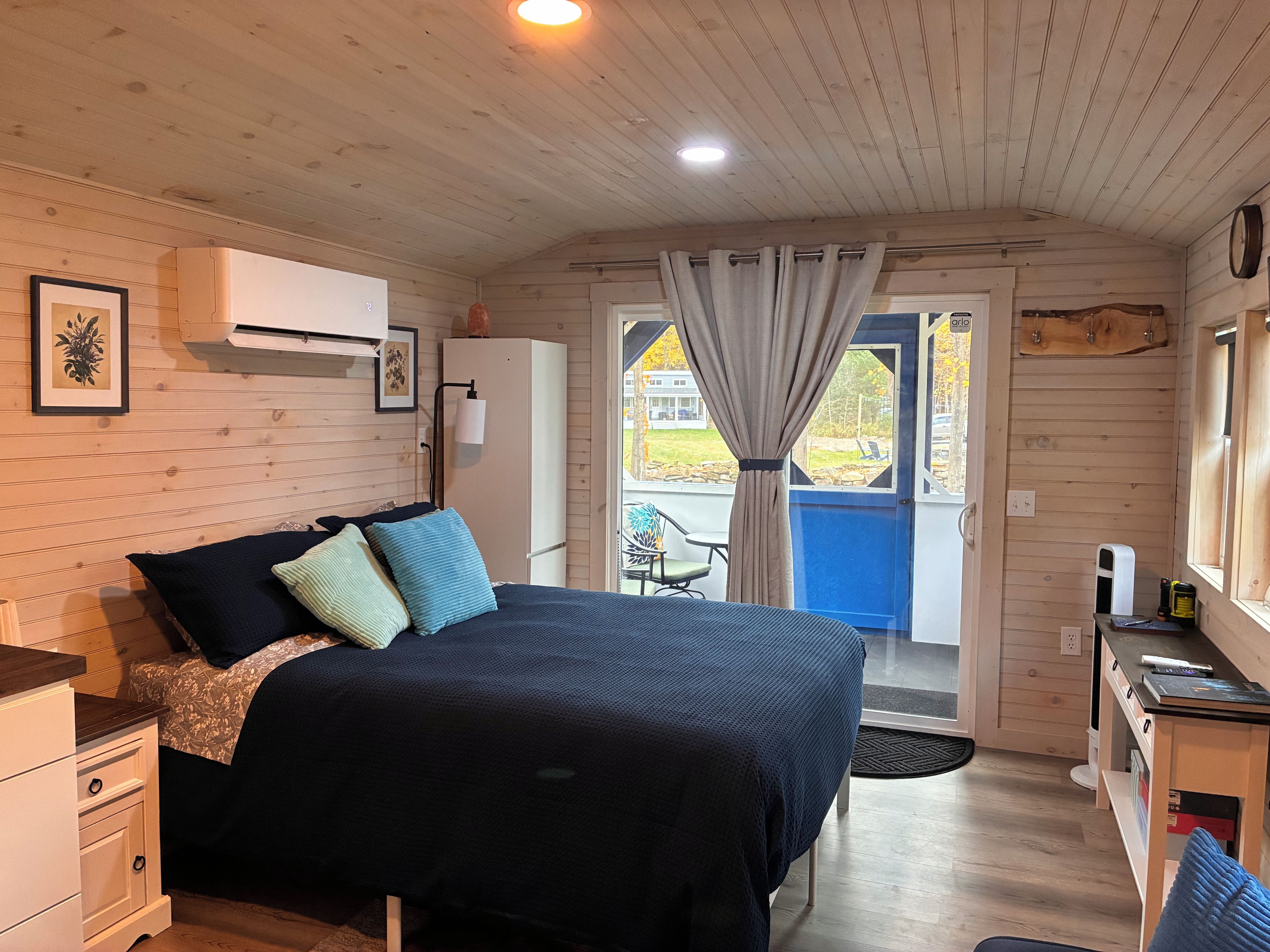 Una habitación acogedora con una cama, un escritorio y un ventanal.