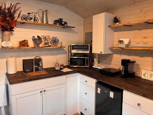 A kitchen with white cabinets, a microwave, a coffee maker, and decorative items on shelves.
