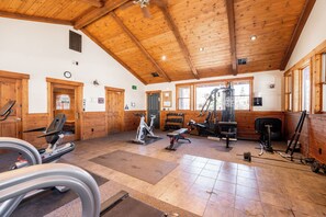 Een sportschool met diverse fitnessapparatuur, houten wanden en een hoge nok.