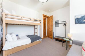 Een slaapkamer met stapelbedden, een houten deur, een tafeltje met een lamp en een radiator aan de muur.