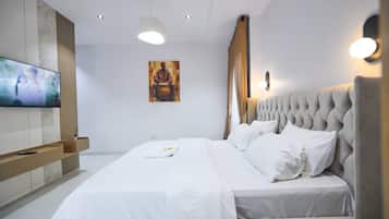 Habitación de hotel moderna con una cama grande, un televisor de pantalla plana, un cuadro en la pared y un banco empotrado.