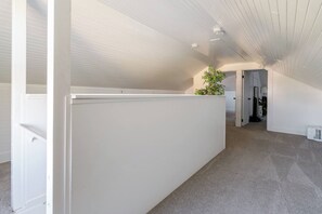 A modern interior with a white partition, a ceiling with recessed lighting, and a plant on the partition. - A Block from Alberta St • 4BR • Sleeps 10 (Portland)