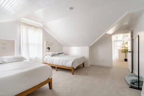 A bedroom with two beds, a sloped ceiling, and a view of the outdoors. - A Block from Alberta St • 4BR • Sleeps 10 (Portland)
