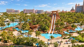 Un resort con varias piscinas, palmeras y un tobogán acuático grande.