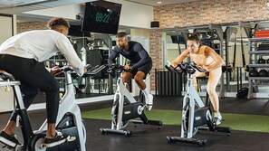Three people on stationary bikes in a gym with a digital clock displaying 09:22. - 2-bedroom resort in beautiful Nassau with fitness room and AC (Nassau)