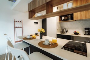 Een moderne keuken met een centraal eiland, witte aanrechtbladen, houten kastjes en een magnetron.