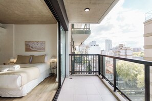 A hotel room with a balcony, a bed, a nightstand, and a city view. - Hestia at Fray Justo Sta. María de Oro 2500 (Buenos Aires)