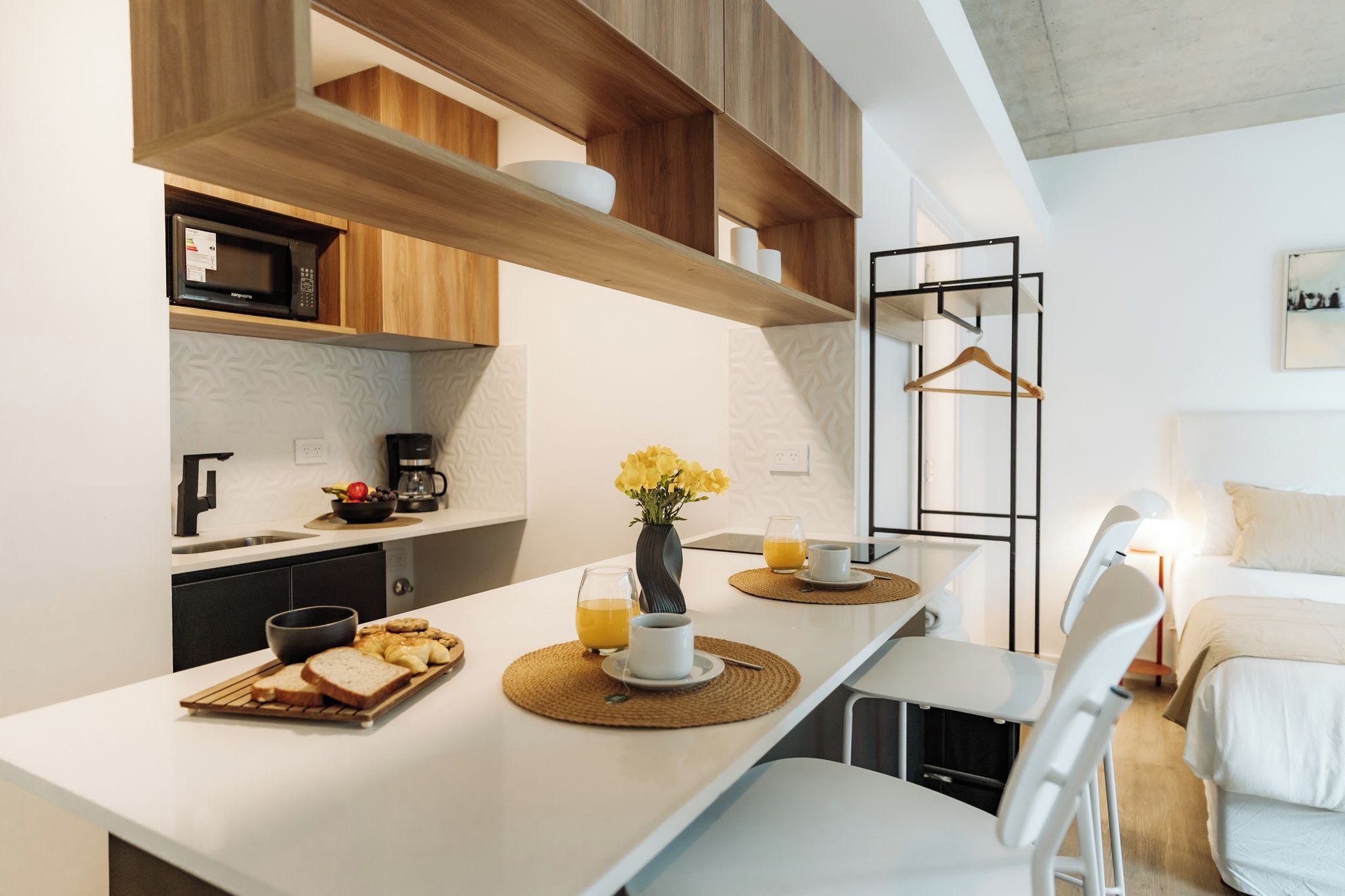 Una cucina moderna con ripiani bianchi, mobili in legno e un'area pranzo con tavolo imbandito per la colazione.