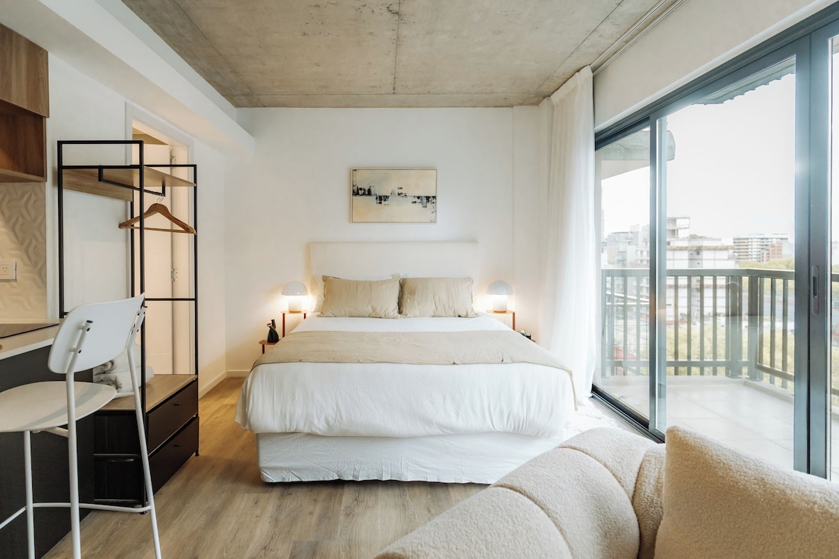 Een moderne slaapkamer met een bed, nachtlampjes, een bureau en een stoel.