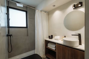 Ein modernes Badezimmer mit Dusche, einem großen Spiegel und einem Waschbecken.