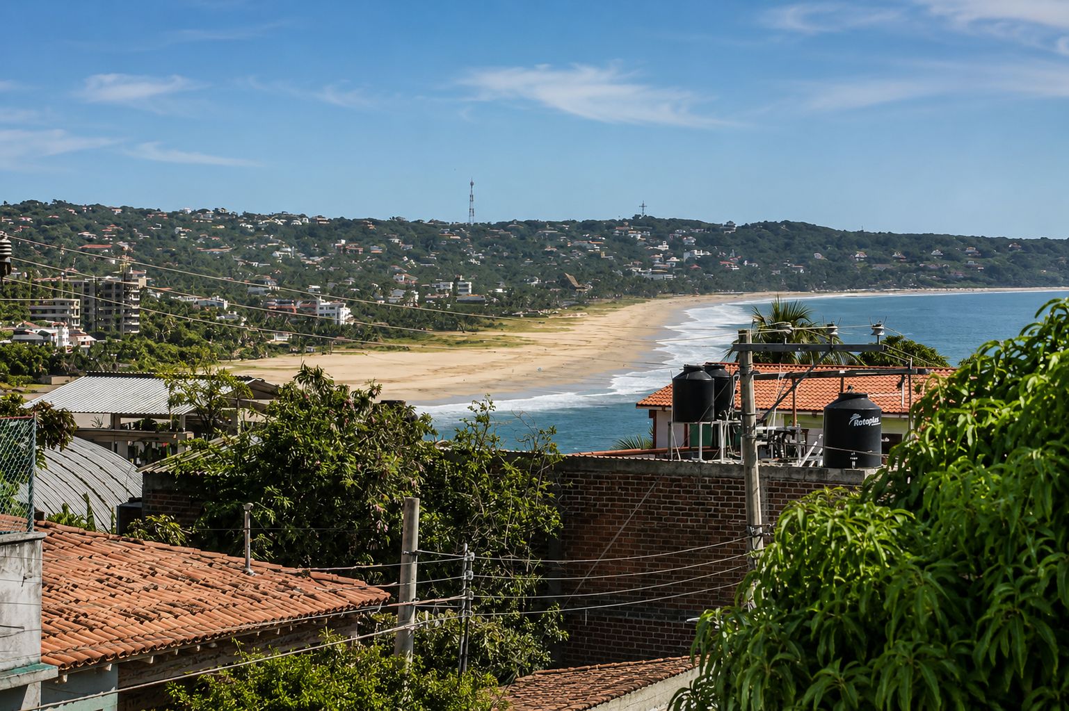 Vista costera con playa, edificios y vegetación.