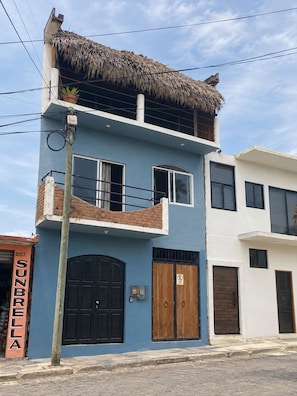 Un bâtiment à deux étages avec une façade bleue, un toit de chaume et un balcon.