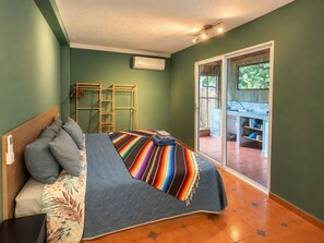 Une chambre comprenant un lit, une table de chevet, une armoire, une fenêtre et une porte-fenêtre coulissante donnant sur un espace extérieur.