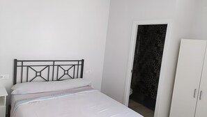 Een slaapkamer met een bed, een kledingkast en een deur naar een betegelde badkamer.