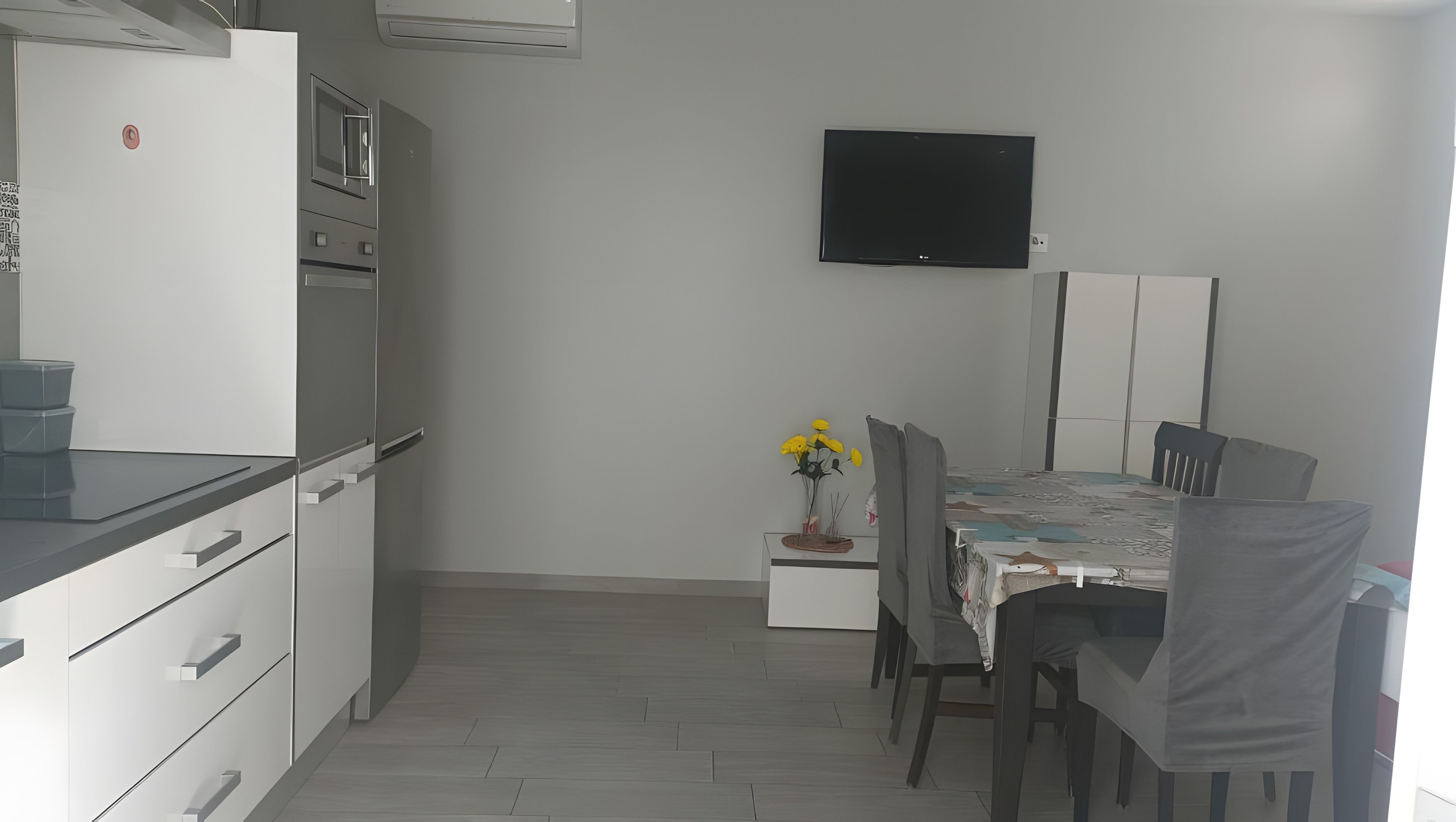 A compact kitchen with a refrigerator, microwave, and a dining area with a table and chairs.