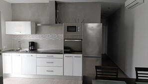 Een moderne keuken met witte kastjes, een magnetron en een koffiezetapparaat.
