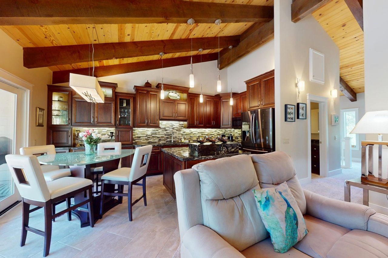 A spacious kitchen with wooden cabinets, a granite island, and pendant lighting.
