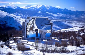 Um edifício moderno com design arquitetônico único, cercado por uma paisagem nevada e montanhas ao fundo.