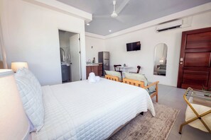 Una habitación de hotel con cama, escritorio, silla, televisión y armario.