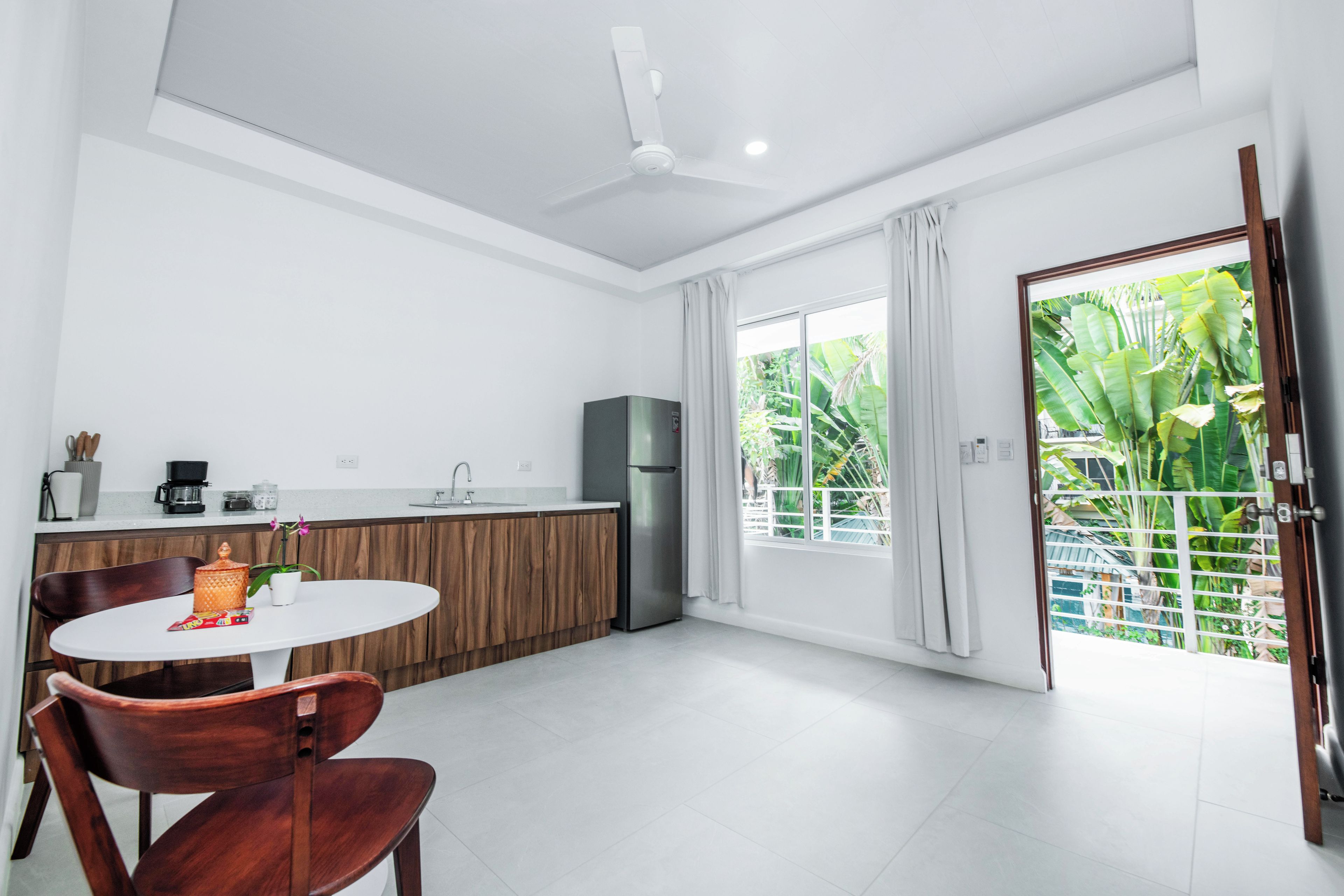 Una cocina moderna con zona de comedor, refrigerador y ventana con cortinas.