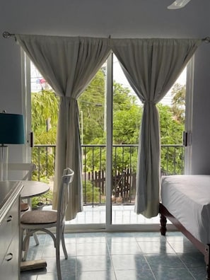Une chambre à coucher avec un lit, une chaise, une table et une fenêtre avec des rideaux.