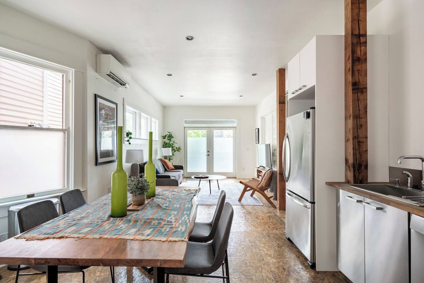 A modern kitchen with a large island, stainless steel appliances, and a dining area with a patterned rug.