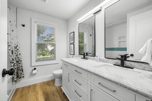 Et moderne badeværelse med to håndvaske, toilet og brusebad.