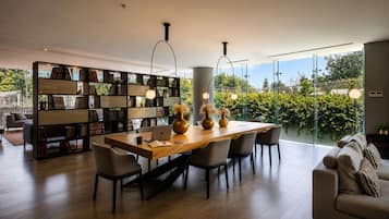 A modern living room with a dining area, large windows, and a bookshelf.