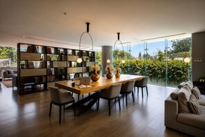 A modern living room with a dining area, large windows, and a bookshelf. - TERRA COTA | Stylish 3BR | Americana (Guadalajara)